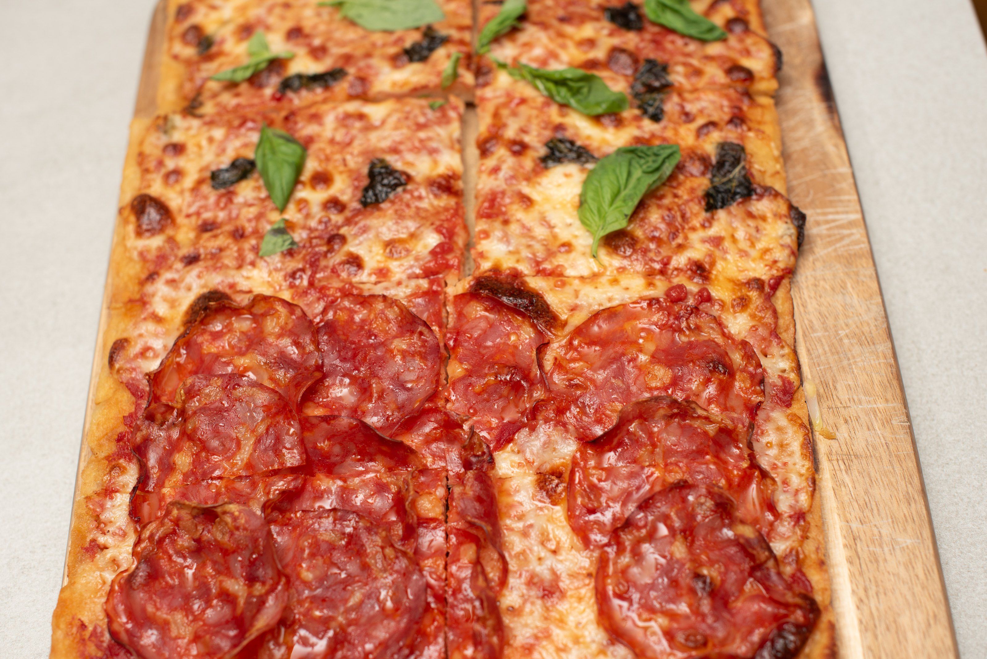 Pizza al taglio with salami and basil, cut into rectangles