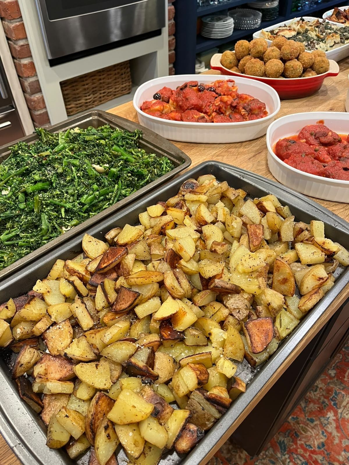 A large tray of roast potatoes, with broccolini and other dishes of the buffet behind it